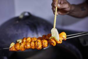 a person holding a skewer of food on a grill at Aureole Mrida - A Boutique Hotel in Lonavala
