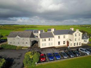 an aerial view of a large white house with parked cars at Aran View Country House in Doolin