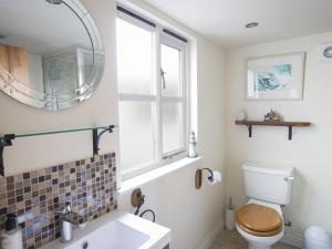 ein Badezimmer mit Toilette, Waschbecken und Spiegel in der Unterkunft Pixie Cottage in Dartmouth + 19 Fotos