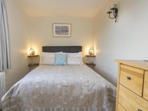 ein Schlafzimmer mit einem Bett mit einem blauen Kissen darauf in der Unterkunft Pixie Cottage in Dartmouth