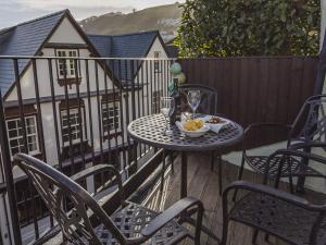 einen Tisch mit Stühlen und eine Schüssel Essen auf dem Balkon in der Unterkunft Pixie Cottage in Dartmouth