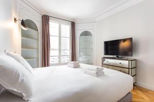 1 dormitorio blanco con 1 cama blanca grande y TV en CMG Batignolles/ Mairie du 17ème, en París
