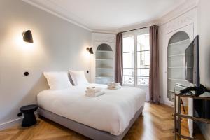 a white bedroom with a large bed and a tv at CMG Batignolles/ Mairie du 17ème in Paris