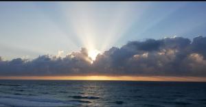 un sol mirando a través de las nubes sobre el océano en Apartment Cancun, en Cancún