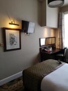 
a hotel room with a bed, desk, lamp and mirror at The Kings Head Inn Wetherspoon in Salisbury
