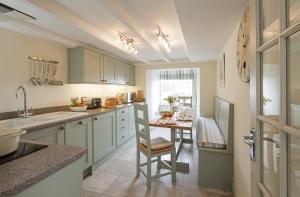 a kitchen with green cabinets and a table with a chair at East Row Lodge in Whitby +6 photos