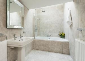 a bathroom with a sink and a tub and a mirror at East Row Lodge in Whitby