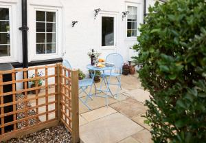 a patio with two chairs and a table in front of a house at Rigg Cottage in Whitby +1 photo