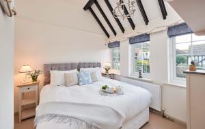 a bedroom with a large white bed and windows at Rigg Cottage in Whitby
