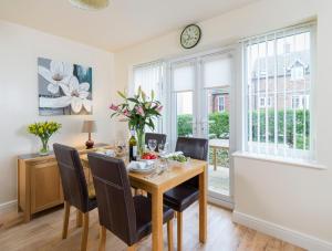 a dining room with a table and chairs and a clock at Sunny Corner Cottage in Filey