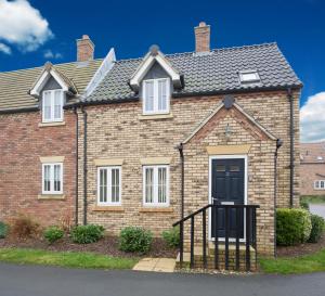 a red brick house with a black door at Sunny Corner Cottage in Filey