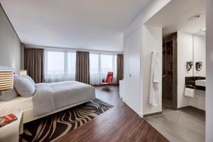 a hotel room with a large bed and a red chair at LEGERE HOTEL Wiesbaden-Taunusstein in Wiesbaden