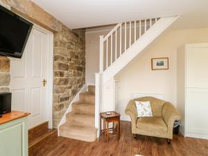 a living room with stairs and a chair and a tv at Bowes Barn in Gateshead