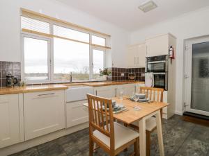 uma cozinha com armários brancos e uma mesa de madeira em 8 Mere View Avenue em Hornsea
