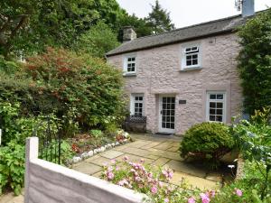a stone house with a garden in front of it at Milkwood Cottage in Fishguard