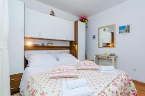 a bedroom with a large bed with pillows and a mirror at Apartments Captain in Dubrovnik