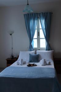 a bedroom with a bed with a blue curtain and a window at Armenaki Apartments in Sampatiki