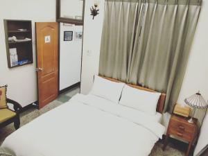 台南的住宿－民生綠園，卧室配有白色的床和窗户。