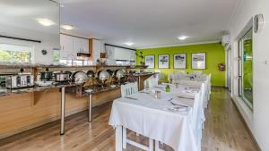 un restaurante con mesas blancas y una cocina en Silver Oaks Boutique Hotel, en Durban