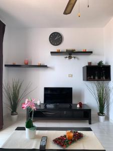 een woonkamer met een bank en een klok aan de muur bij Quiet Studio, Incredible views, Climatized pool, FREE WIFI in Arona