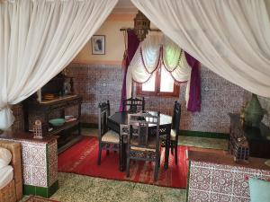 comedor con mesa, sillas y ventana en Dar Khadija, en Asilah