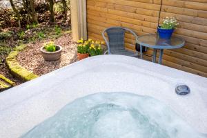 a hot tub in a backyard with a table and flowers at Redlands Country Lodge Apartments with Hot Tubs in Ladybank