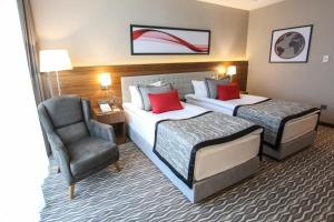 a hotel room with two beds and a chair at Ramada by Wyndham Nigde in Nigde +54 photos