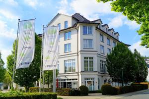 a white building with two flags in front of it at Fletcher Hotel-Restaurant Sundern-Sorpesee in Sundern
