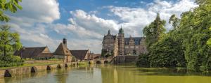 ein altes Schloss mit einem Fluss davor in der Unterkunft B&K Hotels in Vlotho