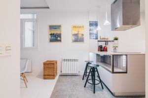 a kitchen with white walls and a counter and stools at Plaza Nueva apartment by People Rentals in Bilbao
