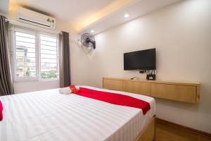 RedDoorz Newstyle Apartment Tran Duy Hung في هانوي: غرفة نوم بسرير وتلفزيون بشاشة مسطحة