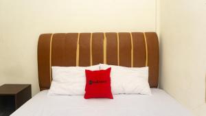a red pillow sitting on top of a bed at RedDoorz near Sentani Airport Jayapura in Jayapura