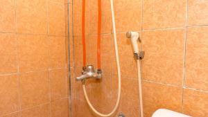 a shower with a hose attached to a wall at RedDoorz near Sentani Airport Jayapura in Jayapura +27 photos