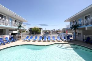 uma piscina com cadeiras azuis e um hotel em Stardust Motel em Wildwood