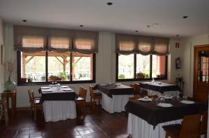 uma sala de jantar com mesas, cadeiras e janelas em Hotel El Jisu em Camaleño