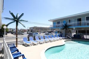 a group of chairs and a swimming pool with a building at Stardust Motel in Wildwood