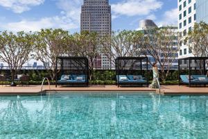 曼谷的住宿－Carlton Hotel Bangkok Sukhumvit，一个带椅子的大型游泳池,享有城市天际线