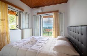 ein Schlafzimmer mit einem großen Bett und einem großen Fenster in der Unterkunft Family Private Homes & Sea View in Lithakia