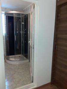 uma casa de banho com uma cabina de duche em vidro e um espelho. em Old Pensiunea Otopeni em Otopeni