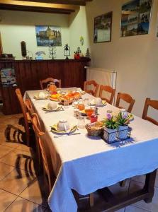 einen Tisch mit einem weißen Tischtuch und Essen drauf in der Unterkunft la ferme des tertres in La Chapelle-près-Sées