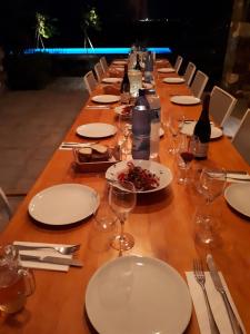 a long wooden table with white plates and wine glasses at Blue Amaryllis Villas in Santa Maria