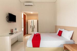ein Hotelzimmer mit einem Bett mit einem roten Objekt darauf in der Unterkunft RedDoorz Syariah @ Kebraon in Kebraon