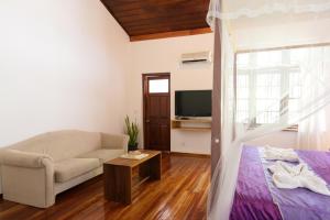 sala de estar con cama, sofá y TV en Sweet Cinnamon Kandy, en Kandy