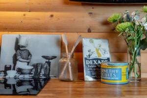 a table with a shelf with pictures and a can and flowers at Redlands Country Lodge Apartments with Hot Tubs in Ladybank