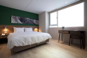 a bedroom with a white bed and a desk and a window at P&F Hotel in Taichung