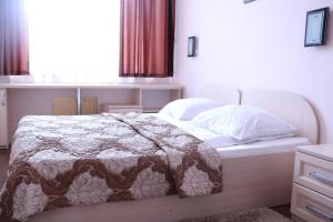 a bedroom with a bed with a comforter and pillows at Hotel Kameliya-v in Vladikavkaz