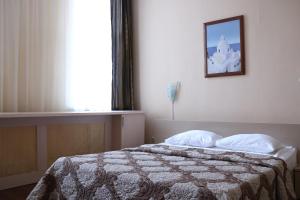 a bedroom with a bed with a blanket and a window at Hotel Kameliya-v in Vladikavkaz