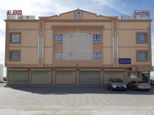 un edificio con dos coches estacionados frente a él en AL JOOD HOTEL APARTMENT, en Ḩilf