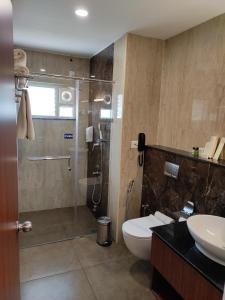 y baño con ducha, aseo y lavamanos. en Hotel Aida en Kottayam