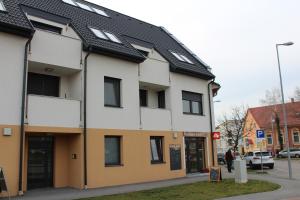 a white and yellow building with a black roof at Quelle-Apartman 2 in Győr